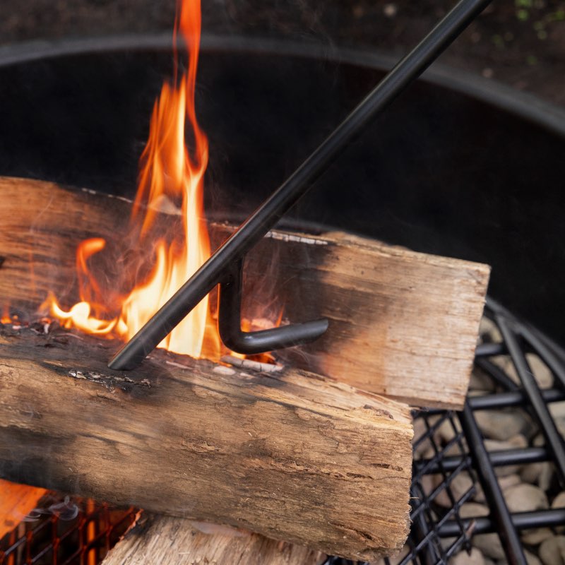 Walden Legacy Series Fire Poker poking firewood inside a fire pit ring