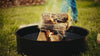 Man adjusting logs with fire poker in Walden fire pit ring with fire grate